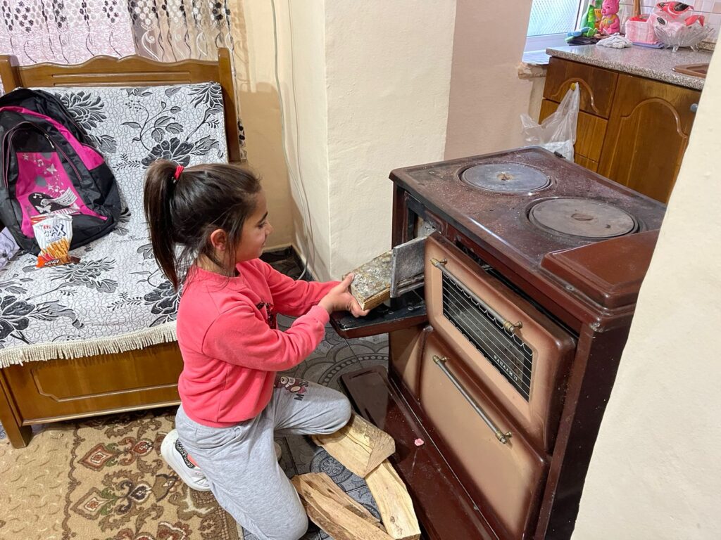 La figlia di Valbona accende il camino con la legna fornita da Islamic Relief